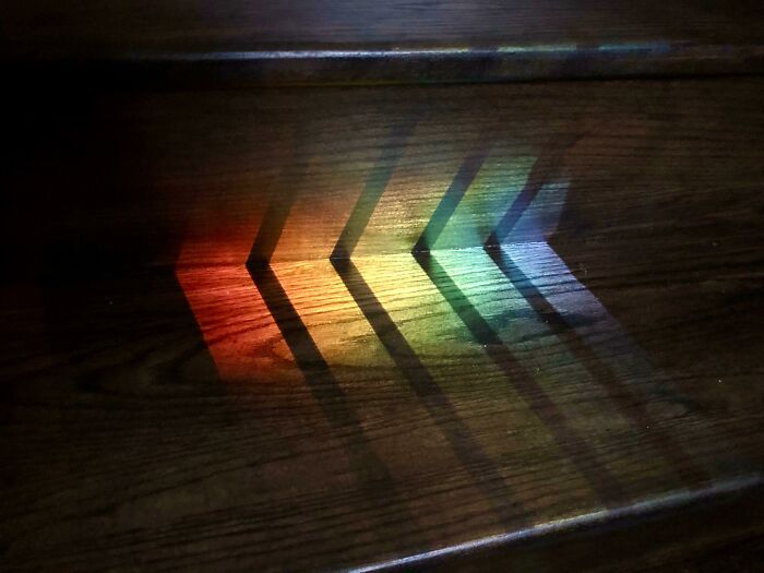 Colorful light creates cool and interesting shadows on a wooden surface, showcasing unique shadow patterns that catch the eye.
