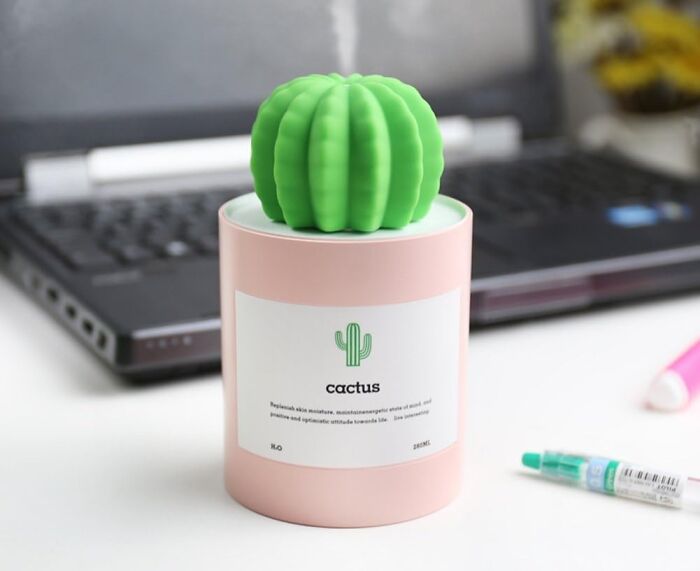 Green cactus-shaped humidifier on pink container near laptop, a seriously sweet discovery to add a major dose of aww.