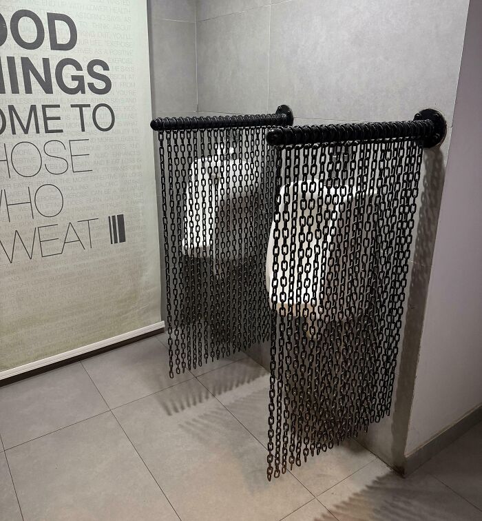 Urinals in a gym restroom with chain curtains, illustrating annoying gym moments and unusual privacy solutions.
