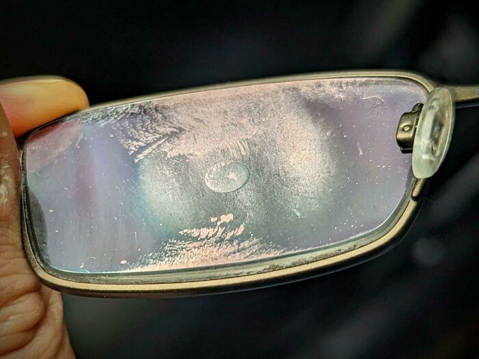 Close-up of a scratched and foggy eyeglass lens showing unusual light patterns in an unreal photograph.