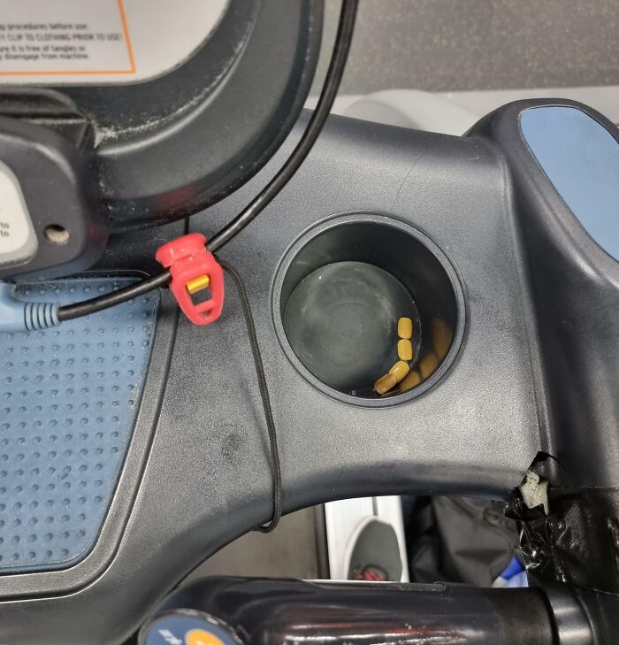 Treadmill cup holder with scattered pills and tangled headphone cord, illustrating annoying gym moments during workouts.