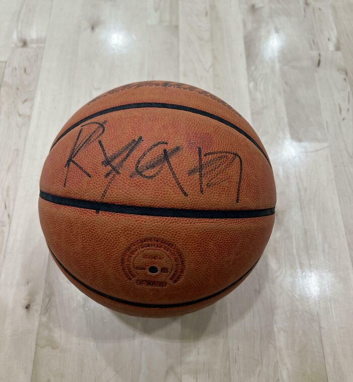 Worn basketball with faded signature sitting on a light wood gym floor, highlighting annoying gym moments.