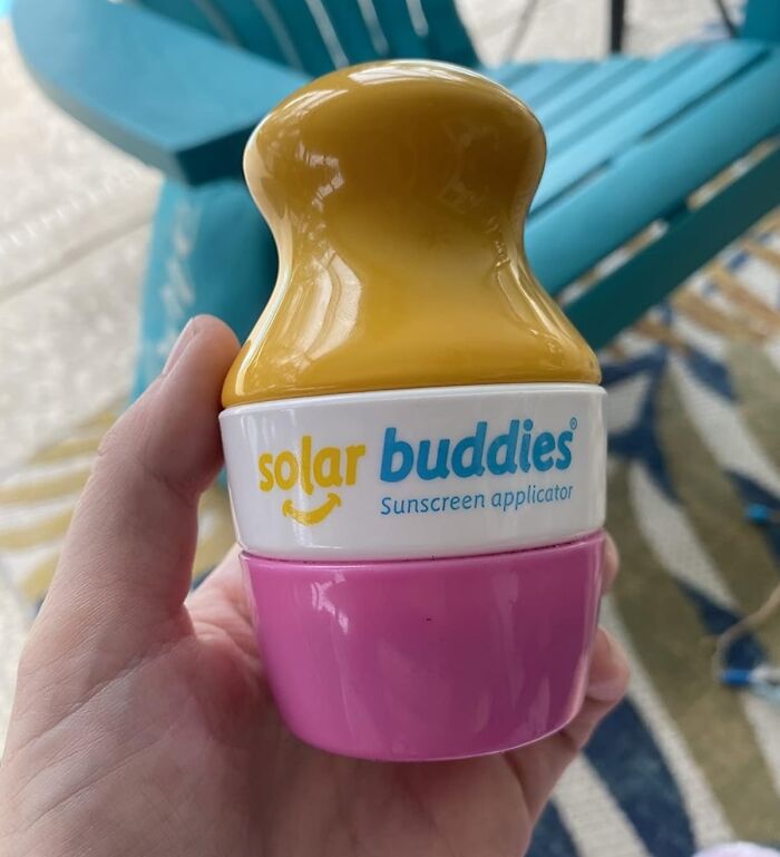 Hand holding a solar buddies sunscreen applicator, a beach day essential to conquer sun, sand, and snack attacks.