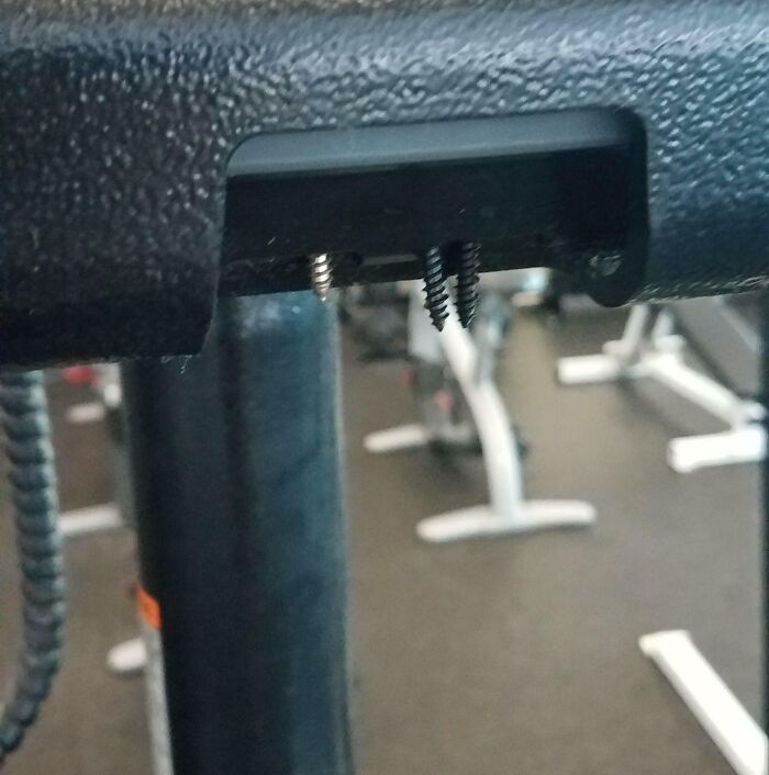 Loose screws hanging from gym equipment frame, showing an annoying gym moment that disrupts workouts and safety.