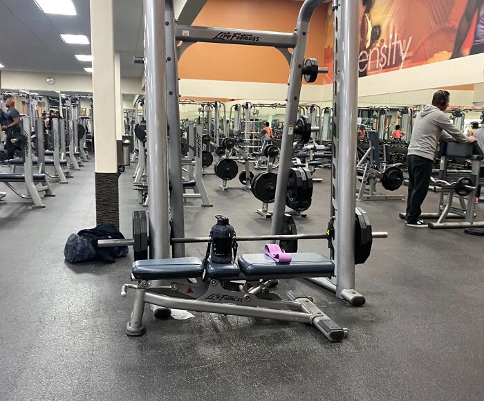 Gym equipment with weights and water bottle, illustrating annoying gym moments during a busy workout session.