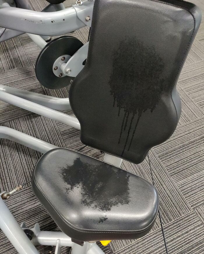Gym seat with large sweat stains on backrest and cushion, highlighting annoying gym moments and discomfort during workouts.