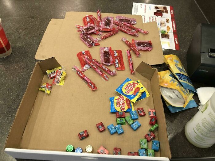 Partially empty candy boxes and scattered wrappers on a cluttered counter in a toxic work environment photo.