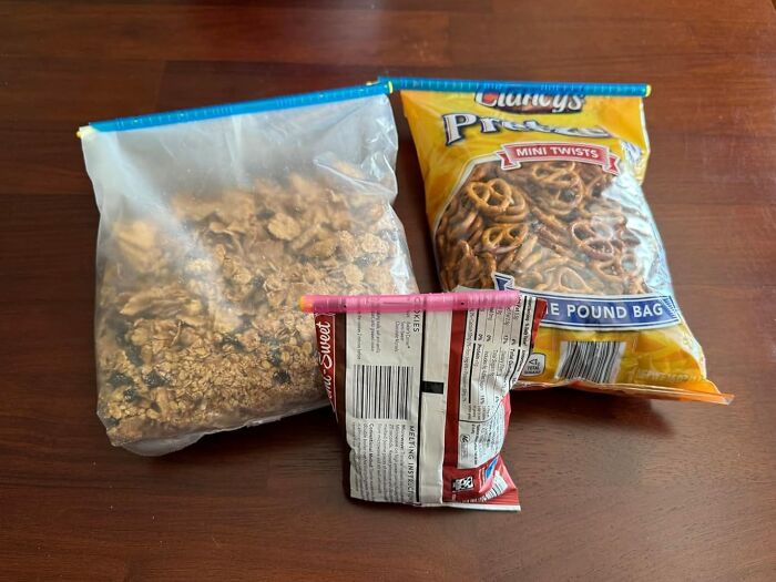 Resealed snack bags with granola, pretzels, and chips on a wooden table, essential for adulting starter pack organization.