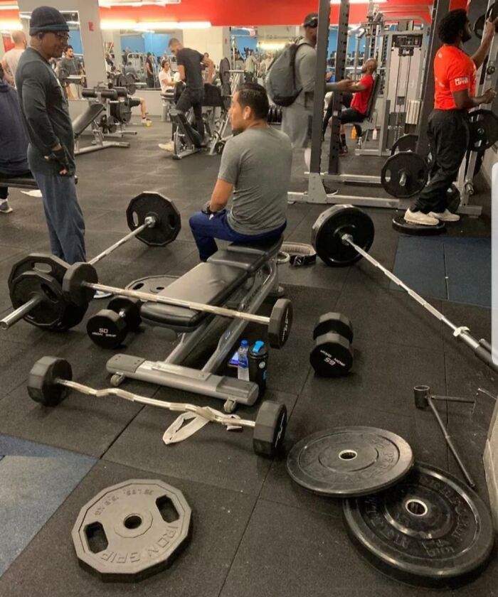 Gym scene showing weights and equipment scattered on the floor, highlighting annoying gym moments disrupting workouts.