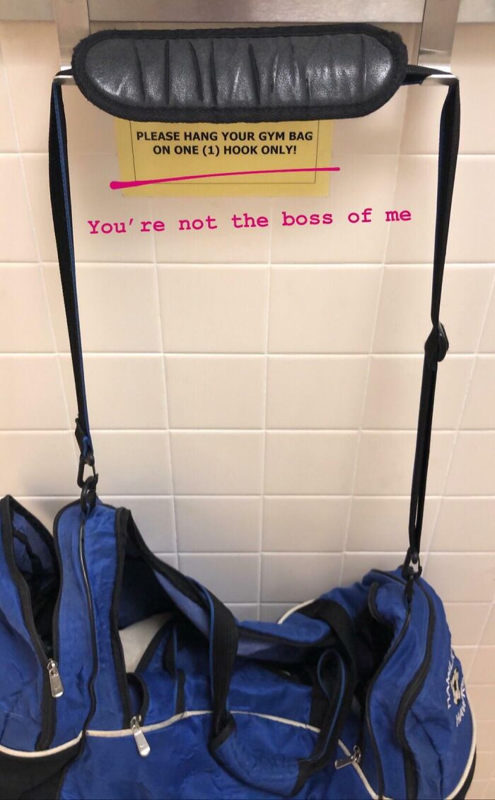 Blue gym bag hanging incorrectly under a sign about gym bag rules, highlighting an annoying gym moment.