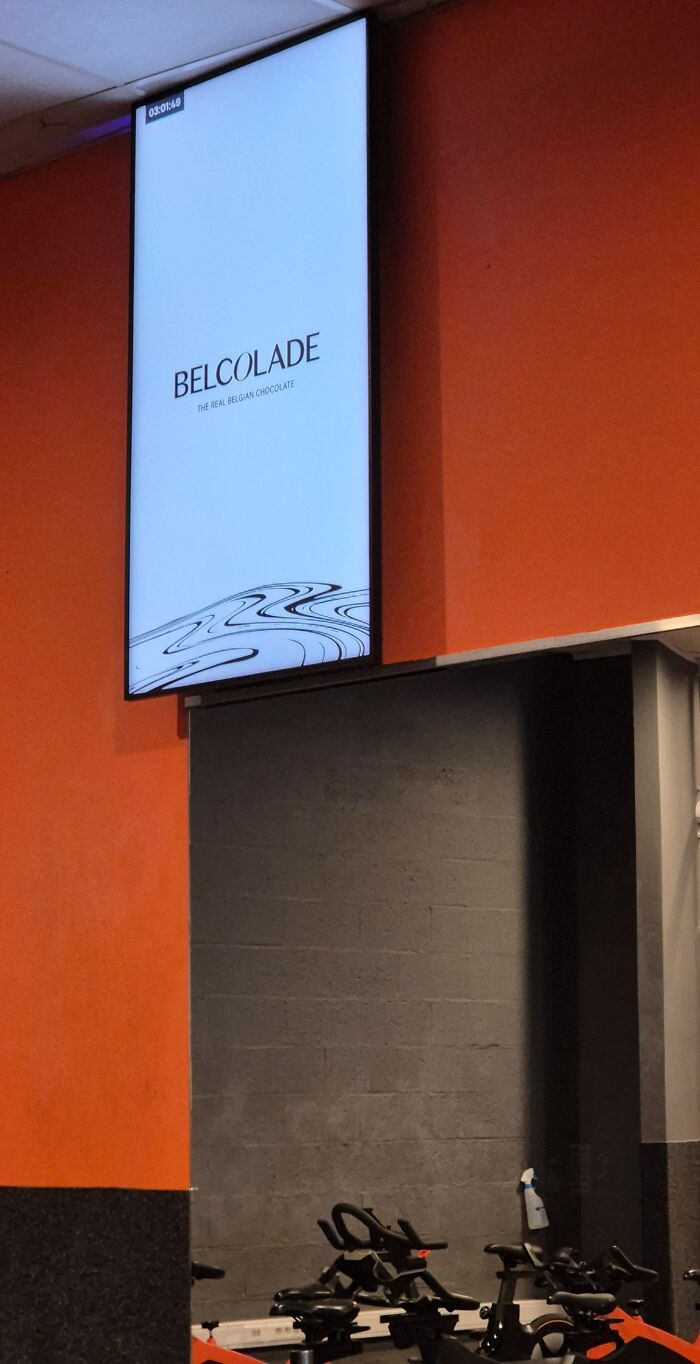 Indoor gym with stationary bikes under an illuminated sign, highlighting annoying gym moments and running in the rain alternatives.