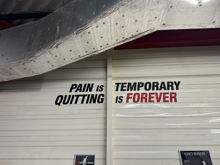 Motivational gym wall text emphasizing pain, quitting, and temporary versus forever mindset in a workout environment.