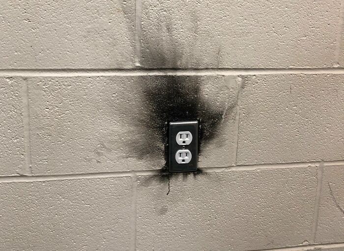 Burnt electrical outlet on concrete wall illustrating annoying gym moments and potential hazards during workouts.
