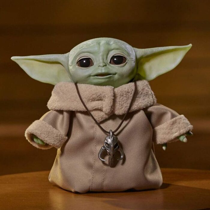 Small green alien figure wearing a tan robe with a pendant, representing bizarre finds that affect your bank account.