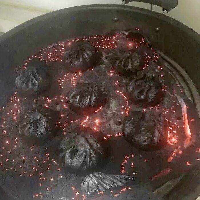 Burnt dumplings on a hot pan with glowing embers, showing a challenging cooking fail in random photos processing.