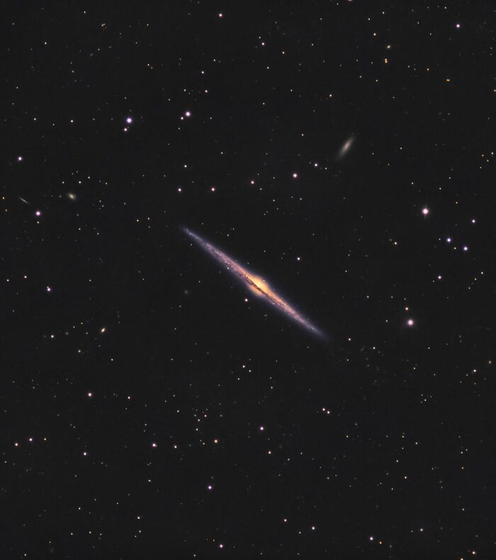 Edge-on galaxy surrounded by stars captured in one of the most unreal photographs showcasing reality stranger than fiction.