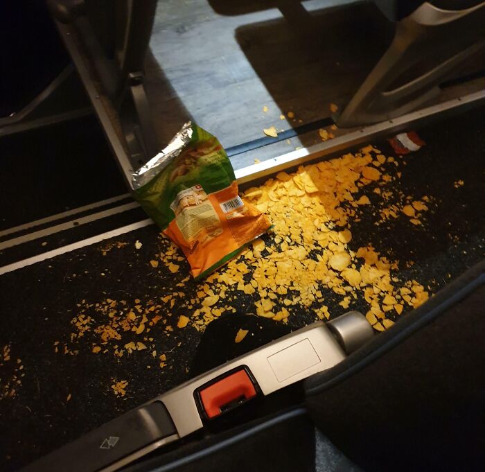 Open chip bag spilled on public transport floor, showing messy and inconsiderate passenger behavior on a bus or train.