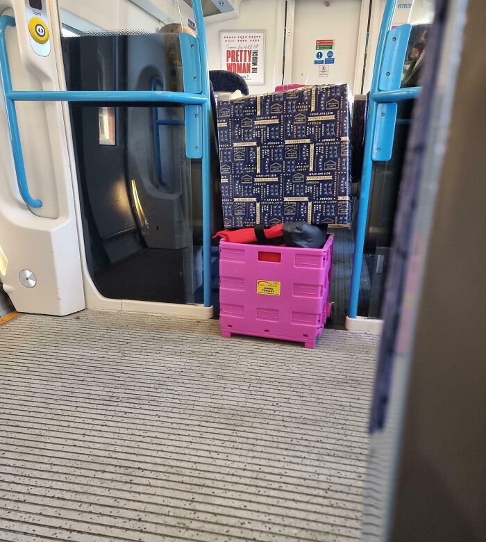 Pink crate blocking aisle on public transport with seat covered by patterned fabric, illustrating infuriating passenger behavior.