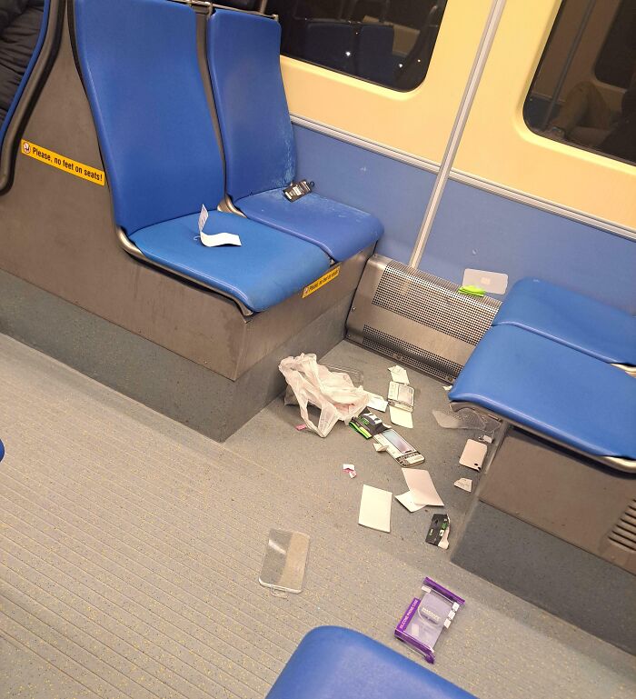 Litter and clutter on the floor of a public transport vehicle with blue seats, showing infuriating passenger behavior.