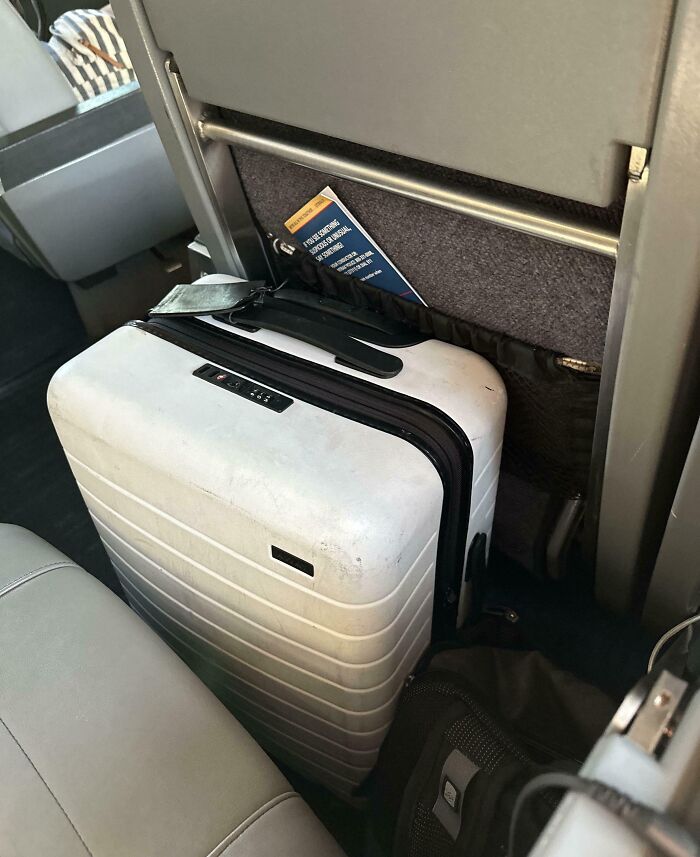 Large suitcase blocking public transport aisle, illustrating infuriating public transport passengers ignoring space rules.