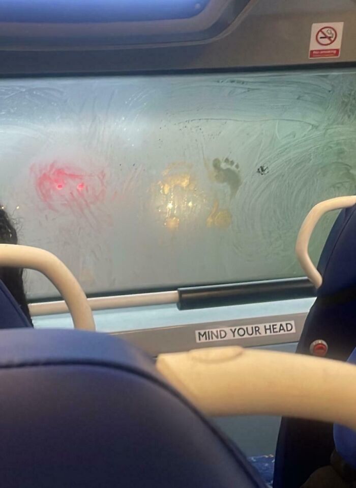 Foggy public transport window with a visible footprint, showing infuriating behavior of public transport passengers.