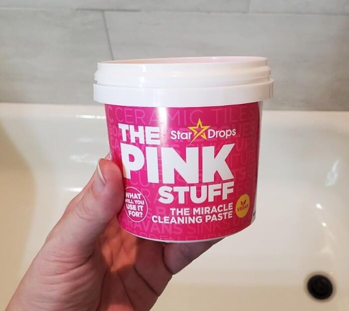 Hand holding a container of chemical-free pink cleaning paste labeled the miracle cleaning paste for eco-friendly use.