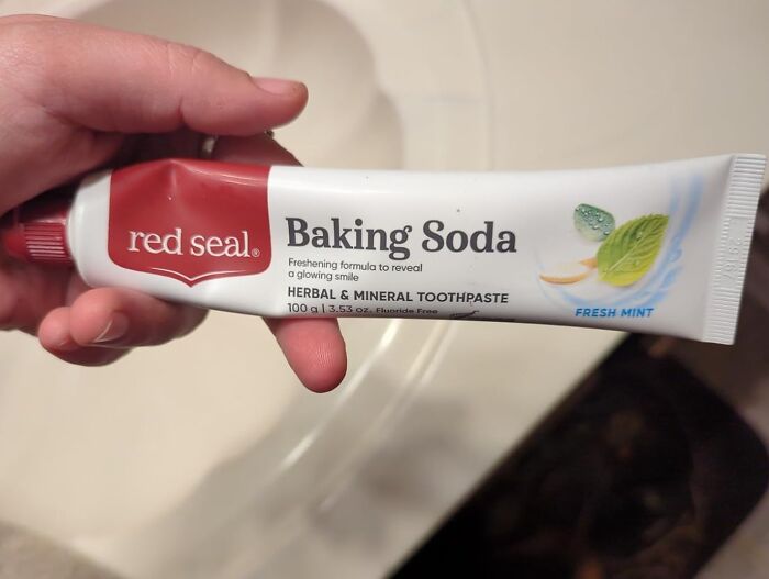 Hand holding a tube of chemical-free baking soda herbal toothpaste, highlighting clean and natural oral care finds.