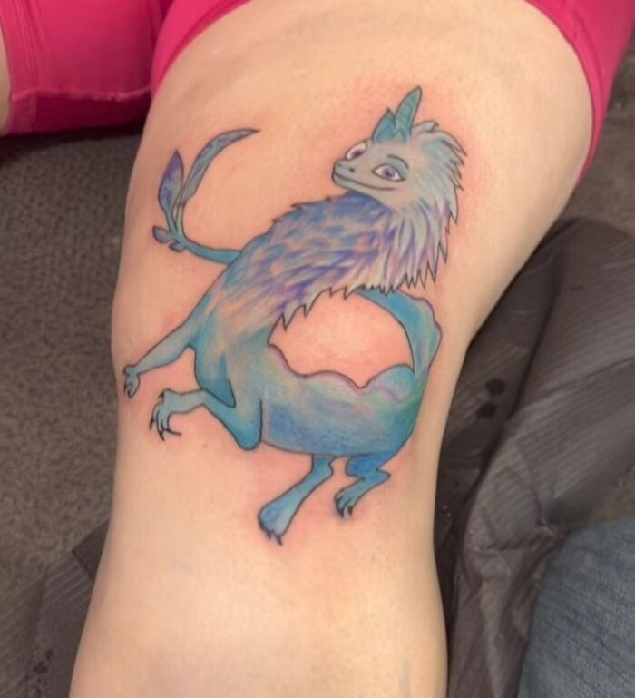 Blue and purple fantasy creature tattoo on leg showing a hilariously bad tattoo example for inkshaming content.