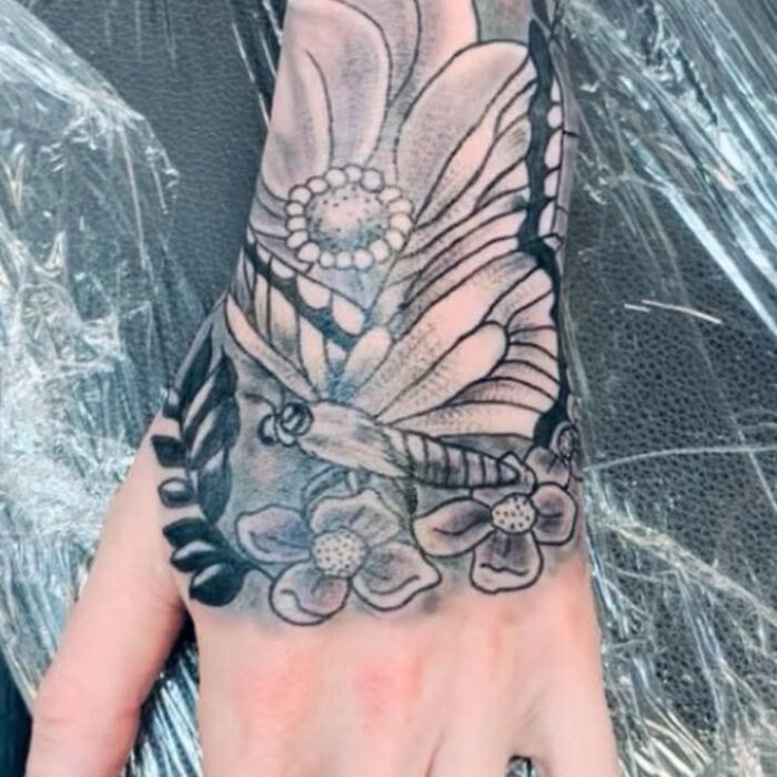 Black and gray butterfly and flower tattoo on hand, an example of hilariously bad tattoos in inkshaming collection.