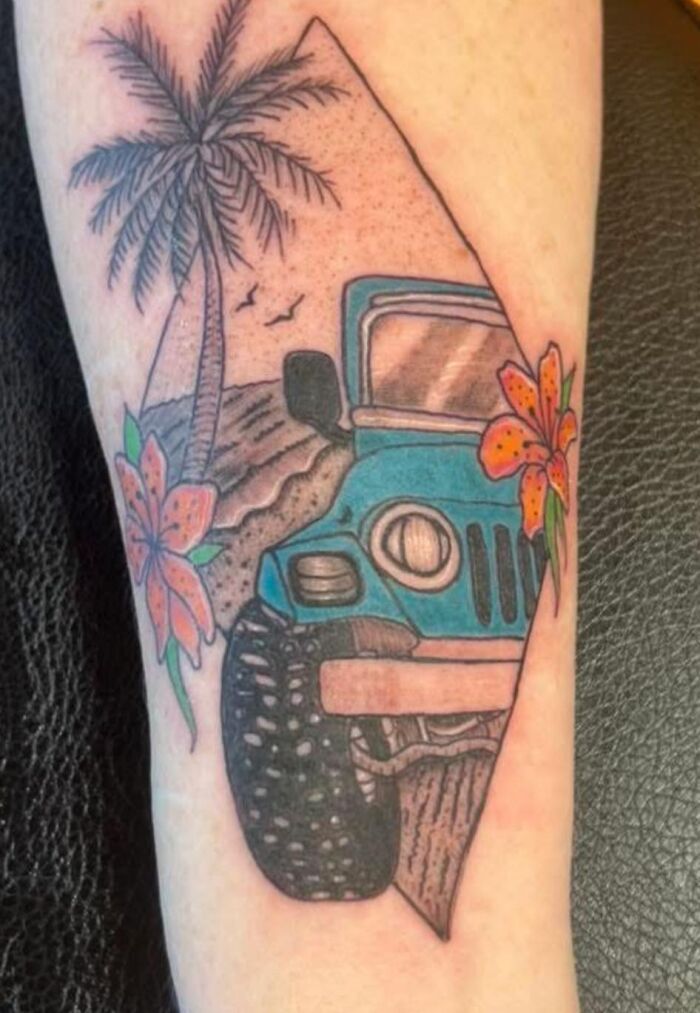 Tattoo of a blue jeep with palm tree, flowers, and birds on a beach, showcasing a detailed and colorful ink design.