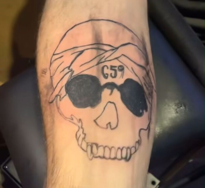 Tattoo of a skull with large black sunglasses and number 659 on forehead, example of hilariously bad tattoos and inkshaming.