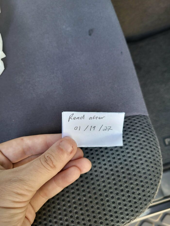 Hand holding a small folded note with a date, one of the historical mementos people randomly found inside a car.