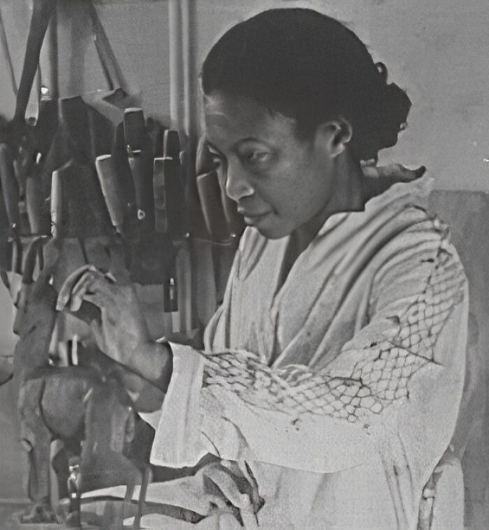 African American woman sculpting wooden art, representing key moments in Harlem Renaissance creativity and culture.