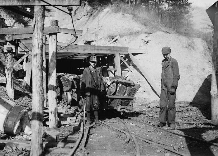 Two miners standing at the entrance of a coal mine, illustrating historical events often overlooked in history.