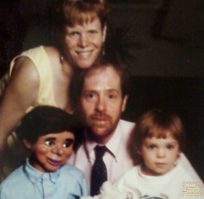 Family portrait with a man, woman, child, and ventriloquist dummy capturing an awkward family moment feeling sweet.
