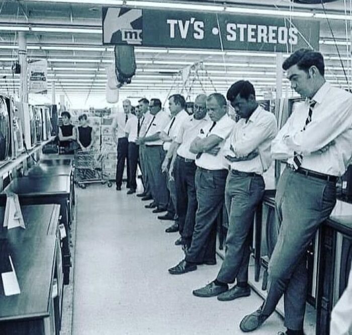 Men lined up in a store aisle looking at TVs, illustrating weird things about history in a vintage setting.
