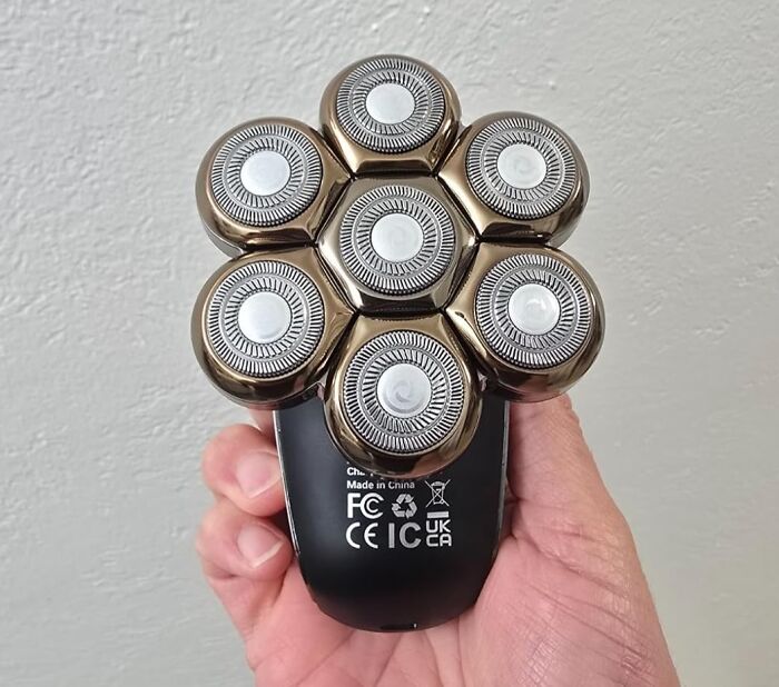 Hand holding a multi-tasking electric shaver with seven rotating heads, a versatile Swiss Army knife of your home.
