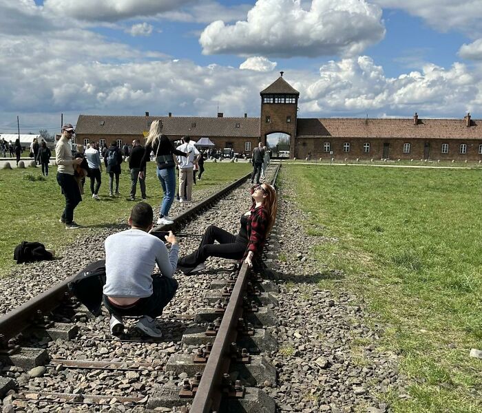 Visitors at the historic site of Auschwitz concentration camp, reflecting on traumatizing the next generation and its impact.