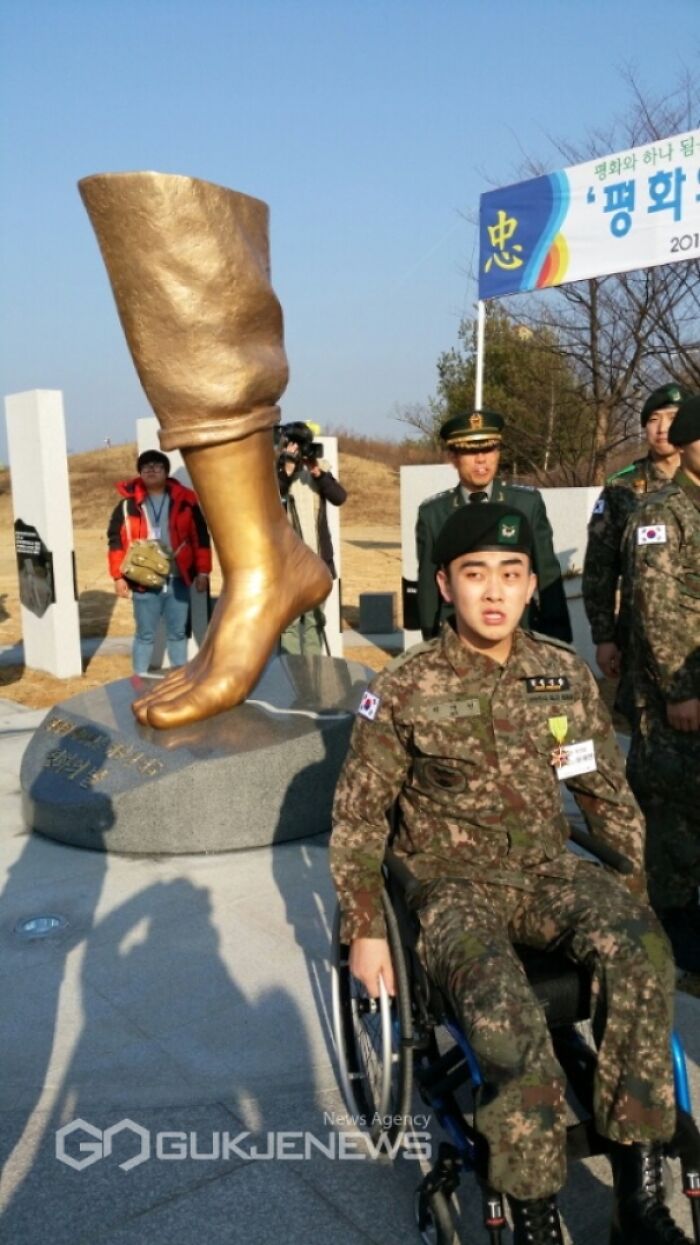 South Korean soldier in wheelchair beside large bronze leg sculpture symbolizing traumatizing the next generation.