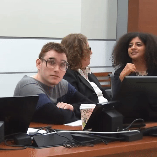 Three young adults in a courtroom setting, discussing serious matters related to traumatizing the next generation.
