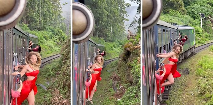Influencer in a red dress dangerously hanging off a moving train in a forested area for views and social media attention.