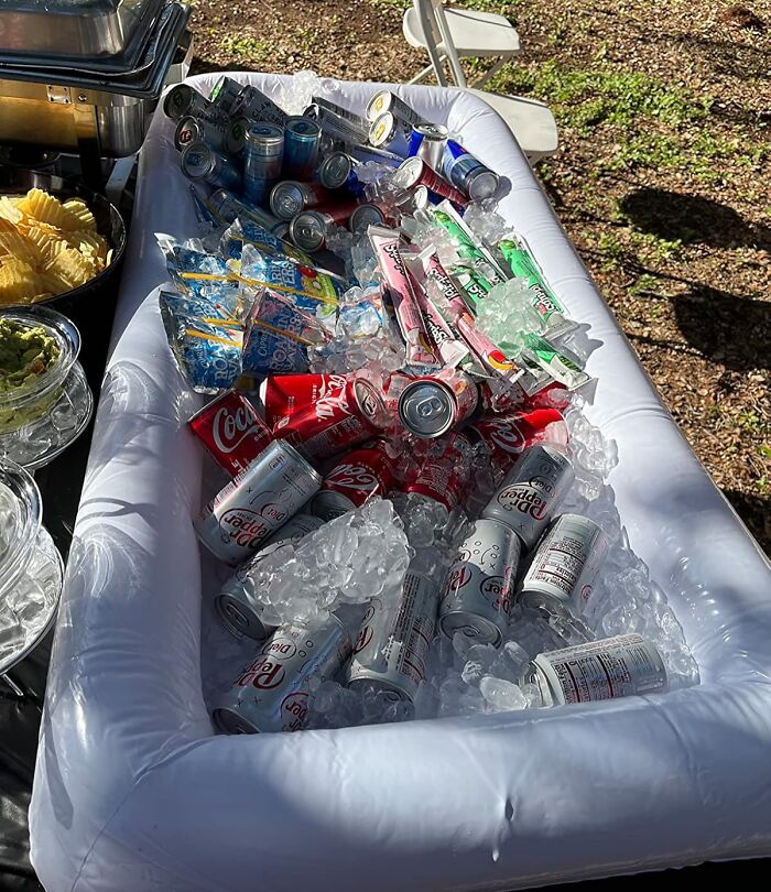 Inflatable cooler filled with soda cans and ice, a must-have for backyard July 4th parties and outdoor gatherings.