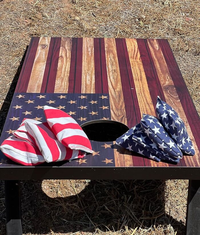 American flag themed cornhole board with red and white striped and blue star bean bags for backyard July 4th parties.