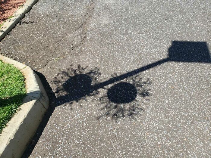 Shadow of a streetlight on pavement creating cool and interesting shapes that made people look twice.