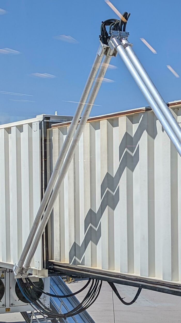 Metal beams casting a cool zigzag shadow on a building wall, an interesting example of shadows that make people look twice.