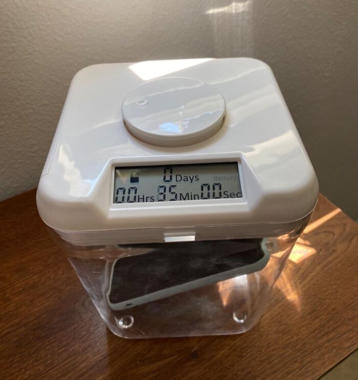 White digital timer on a clear container placed on a wooden table solving a hyper specific life issue with smart design.