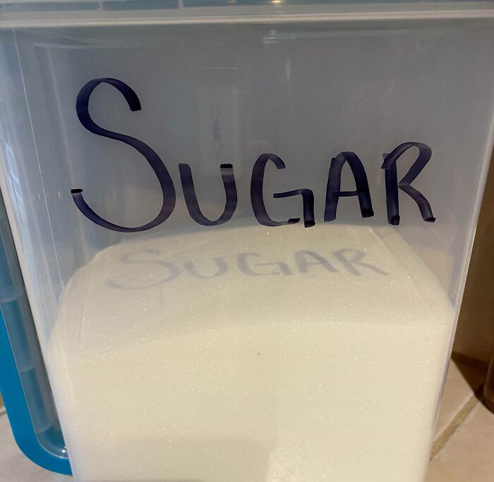 Container labeled sugar casting a clear shadow of the word sugar on the white contents, a cool interesting shadow effect.