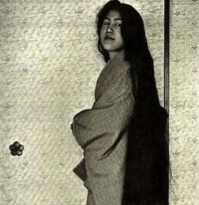Vintage photo of a woman in traditional clothing with extremely long hair, capturing a weird thing about history.