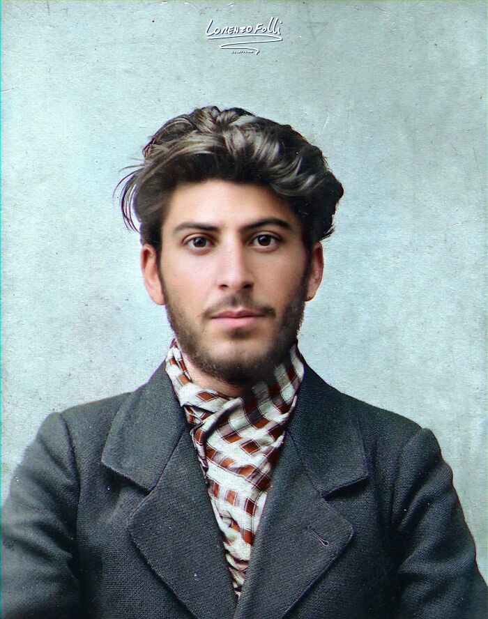 Colorized history pic of a young man with dark hair wearing a patterned scarf and dark jacket against a plain background.