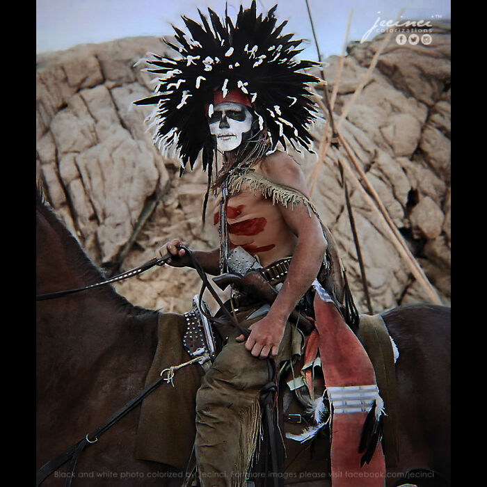 Indigenous warrior in traditional attire and face paint, photographed in an interesting colorized history pics collection.